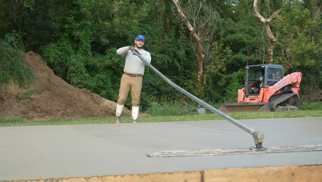 Skilled concrete worker smoothing large outdoor concrete slab